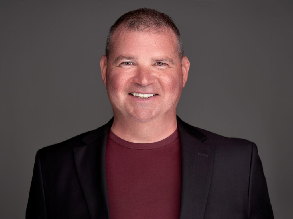 profile photo of Scott Herrick in a dark suit jacket and fitted maroon t-shirt