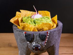 guacamole in a traditional molcajete with tortilla chips on top