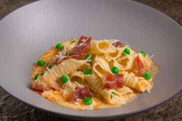 garganelli pasta in a bowl with cream sauce peas and prosciutto