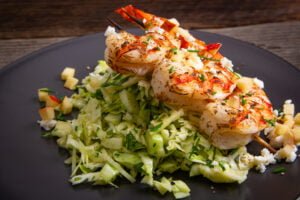 crunchy green salad with cabbage and fennel topped with grilled shrimp